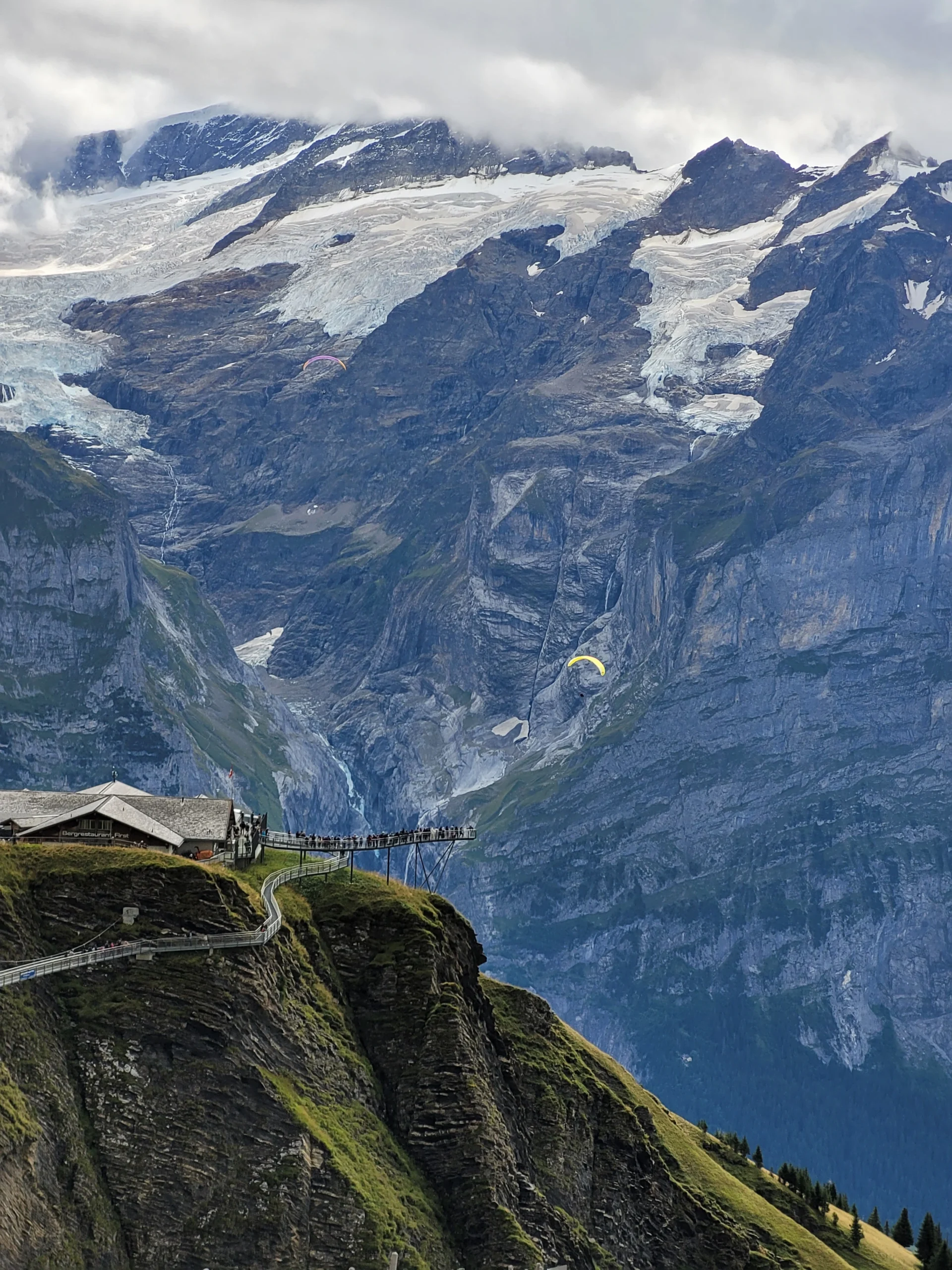 Paragliders above a glacier valley at First viewpoint in the Swiss Alps